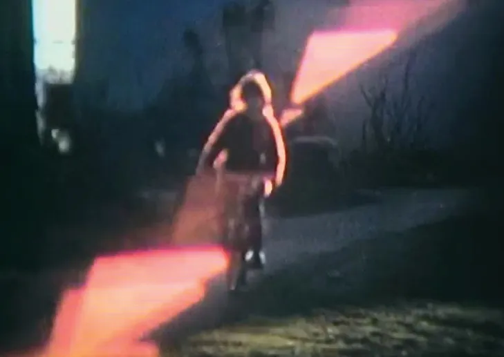 A girl riding a bicycle through a pink light leak