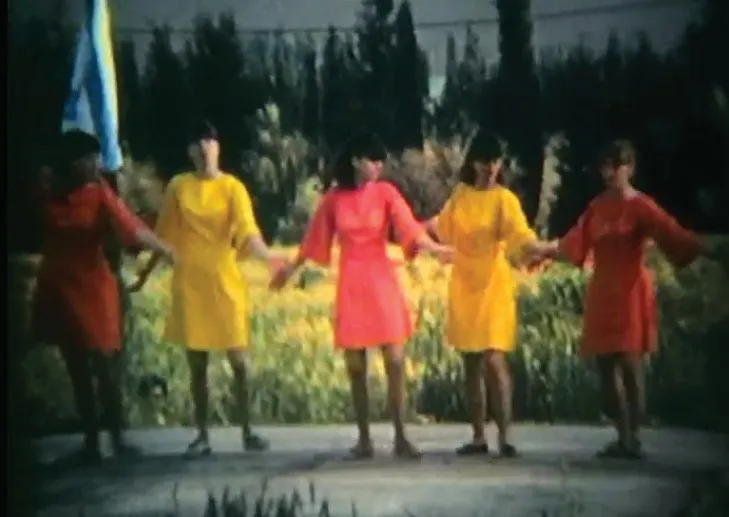 Five girls in red, pink and yellow dresses holding hands in a row